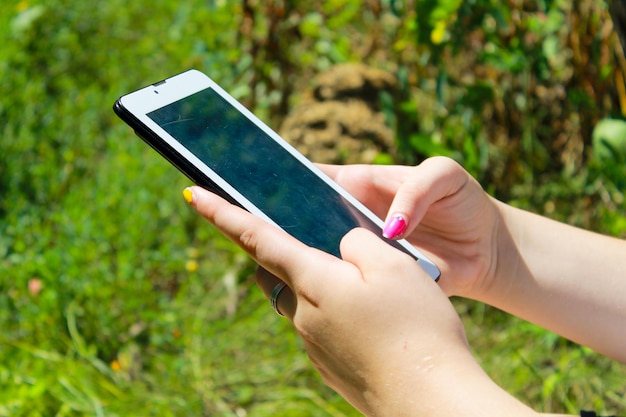 Woman's hands holding a tablet laying on grass