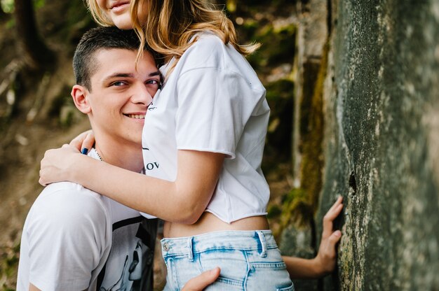 Woman's hands hug men on background large stone walL