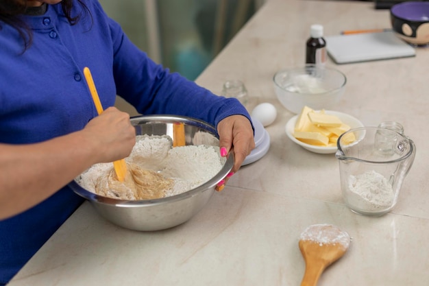 Woman's hands mixing ingredients in a bowl with a spoon to prepare bread