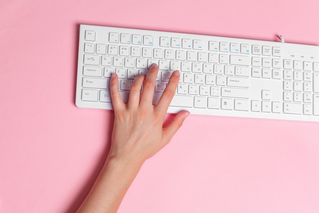 Woman's hands on a pink office workspace view from above