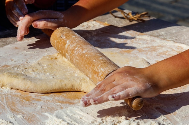 Woman's hands rolling out a dough with rolling pin