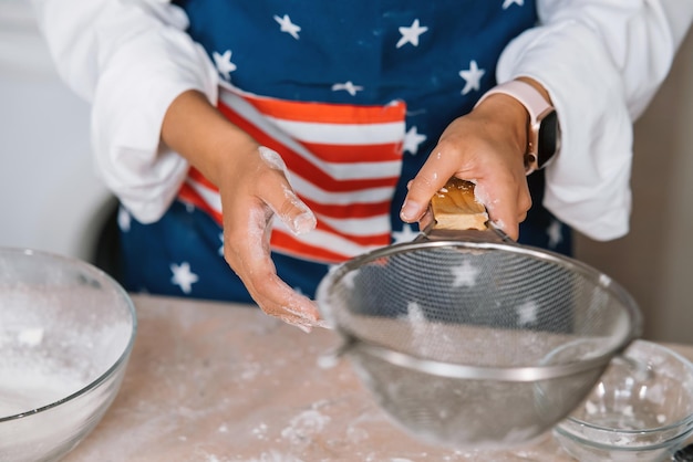 Woman's hands sifting flour through sieve Selective focus