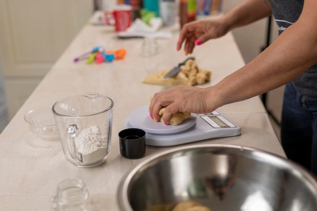 Woman's hands weighing portions of dough to make pan de muerto at her kitchen counter