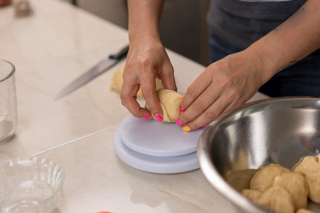 Woman's hands weighing portions of dough to make pan de muerto at her kitchen counter