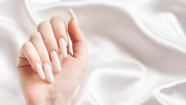 A woman's hands with a manicure on them the nails are painted in a white color