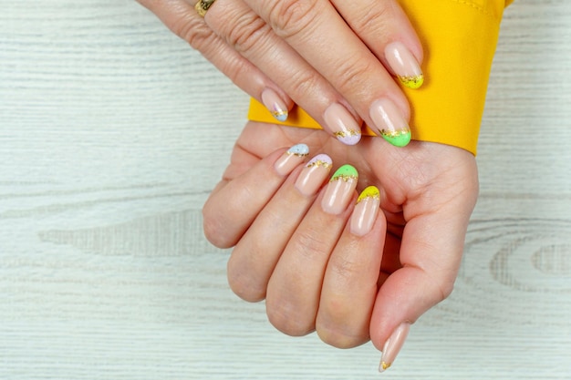 A woman's hands with a yellow and green manicure on their nails