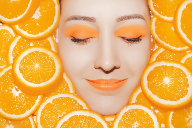 Woman's portrait with oranges closeup Bright orange make up