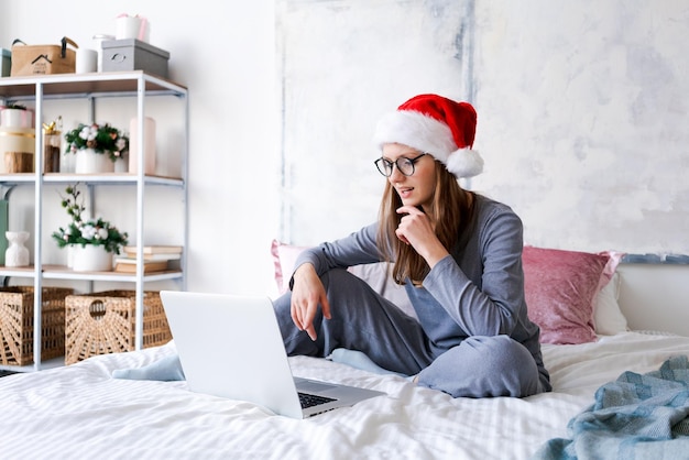 Woman in santa hat playing on laptop at christmas online shopping for holidays