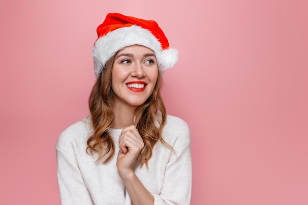 woman in santa hat smiling and holding red gift box