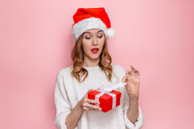 woman in santa hat smiling and holding red gift box