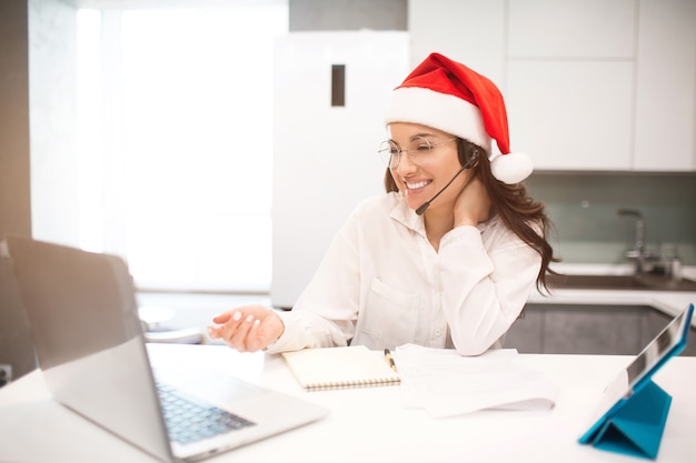 Woman in Santa hat working on a laptop