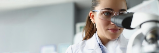 Woman scientist chemist looking through microscope in laboratory