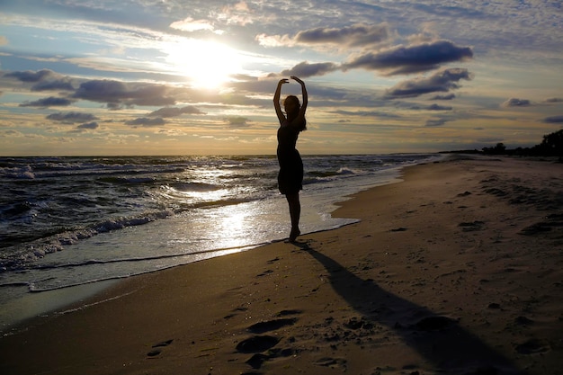 Woman on the sea coast on sunset