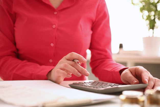 Woman secretary counts on calculator in office closeup