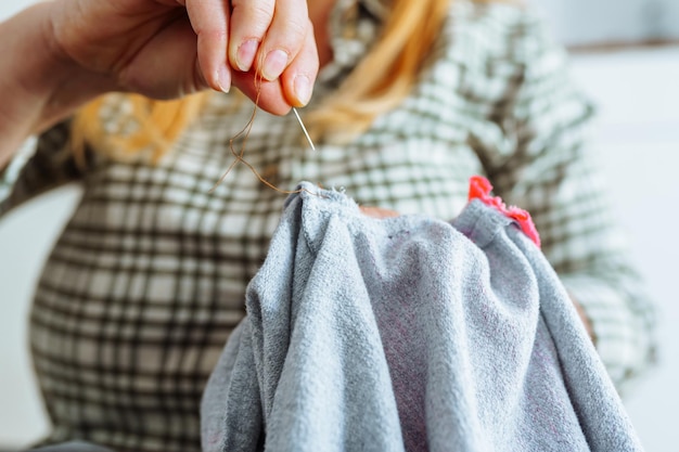 Photo woman sewing up hole in clothes handmade