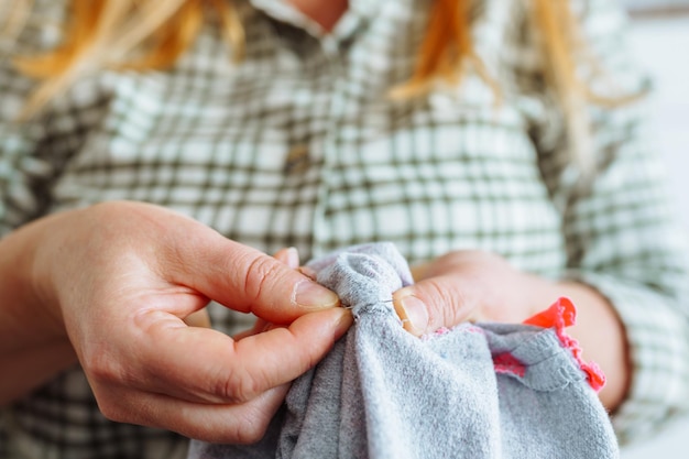 Photo woman sewing up hole in clothes handmade