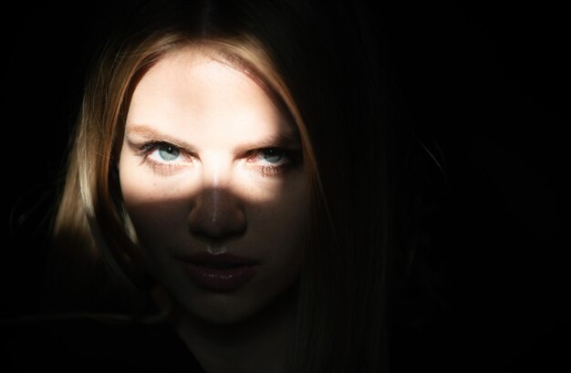 Woman in shadow female serious model with shadows on face looking seductive and sensual on dramatic