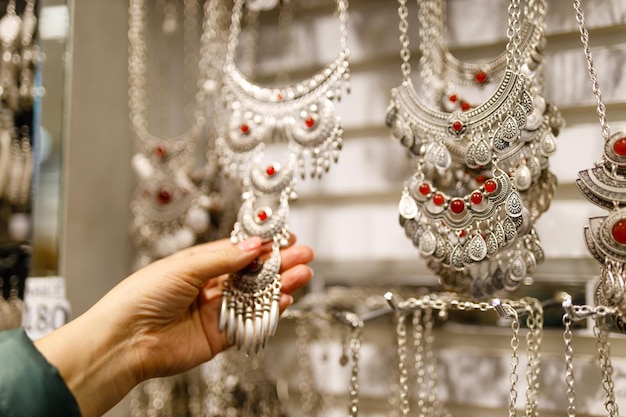 Woman shopping imitation jewellery in store looking for necklace