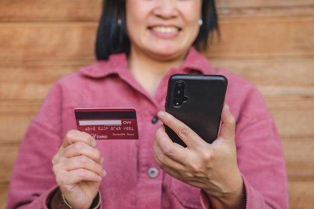 Woman shopping online with credit card at coffee shop in outdoorclose up hand holding smartphone