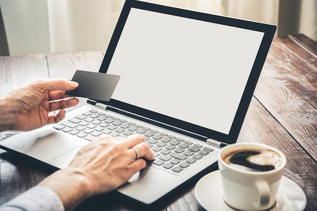 Woman shopping with credit card by laptop in office