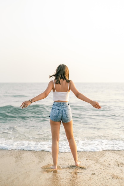 Woman on the shore of the beach from behind