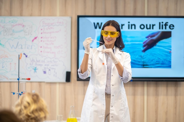 Woman showing chemistry experiment to kids in class