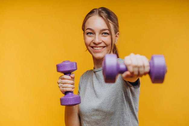 Woman showing exercises with dumbbells in studio