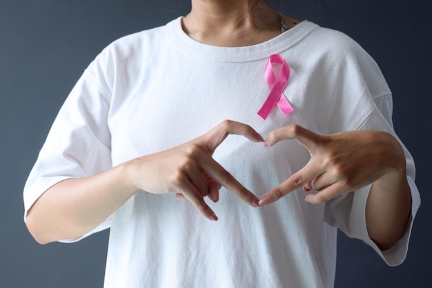 Woman showing love finger for cancer survivor wearing white tshirt and pink breast cancer ribbon