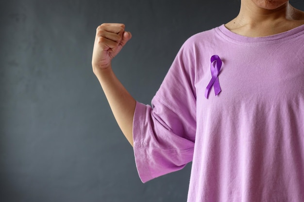 Woman showing strong hand gesture wearing purple shirt and ribbon Symbol of Domestic Violence Awar