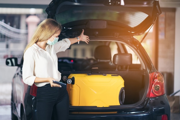 woman showing suitcase in car trunk