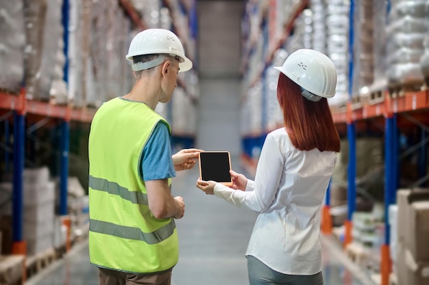 Woman showing tablet to worker with back to camera