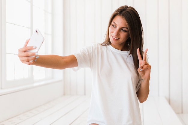 Woman showing V sign and taking selfie