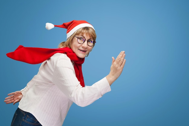 Woman shows running. A middle-aged woman in the new year and Christmas clothes on a blue background