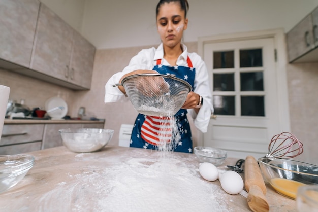 Woman sifting flour through sieve Selective focus