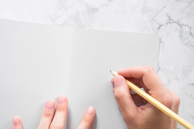 Woman signs gray greeting card on marble table background