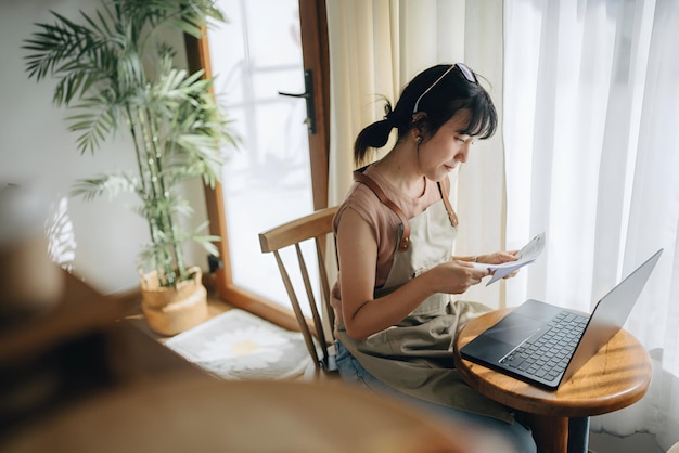 a woman sits in a chair with a laptop and a potted plant