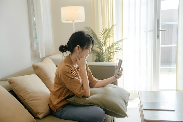 a woman sits on a couch and looks at a phone