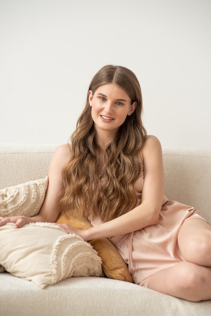 A woman sits on a couch with a pillow on her lap