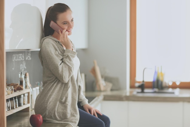 A woman sits on a counter talking on a phone.