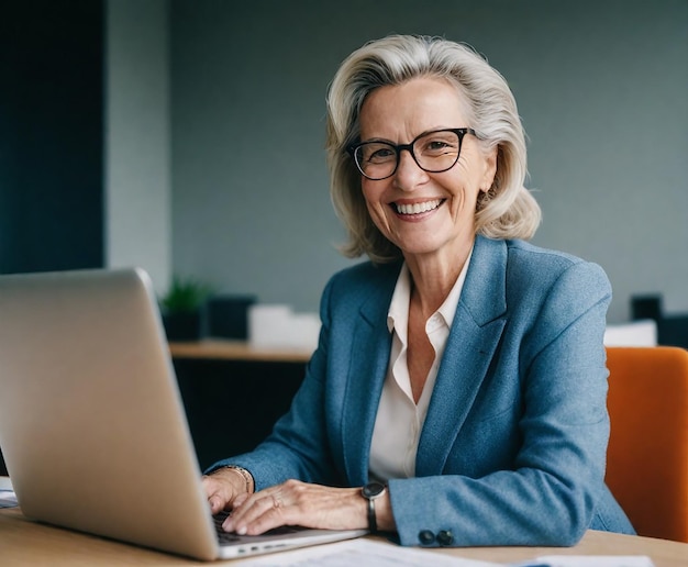 a woman sits at a desk with a laptop and a pen in her hand