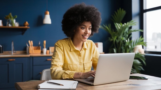 a woman sits at a desk with a laptop and a plant in the background