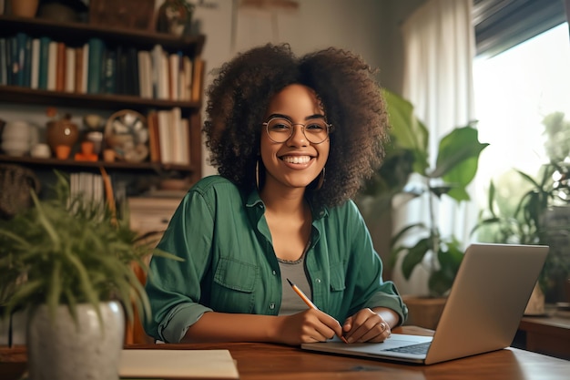 A woman sits at a desk with a laptop and smiles at the camera