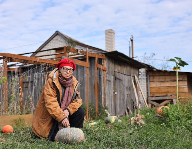 a woman sits in front of a wooden house with a pumpkin in front of it