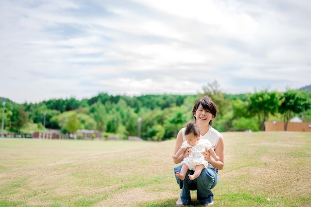 A woman sits on a lawn with her baby