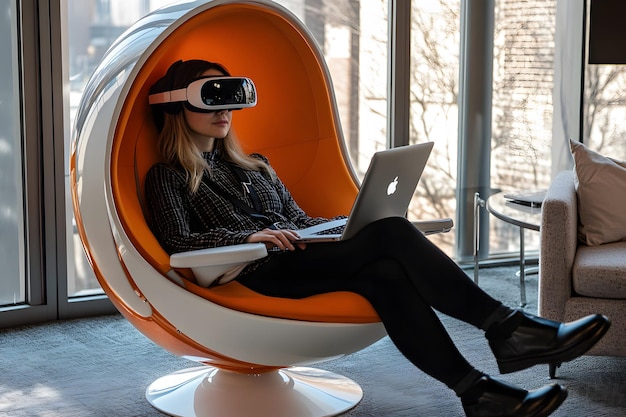 Photo a woman sits in an orange chair with a laptop and a book on her lap