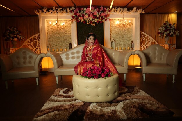 a woman sits on a round ottoman in a room with a floral arrangement