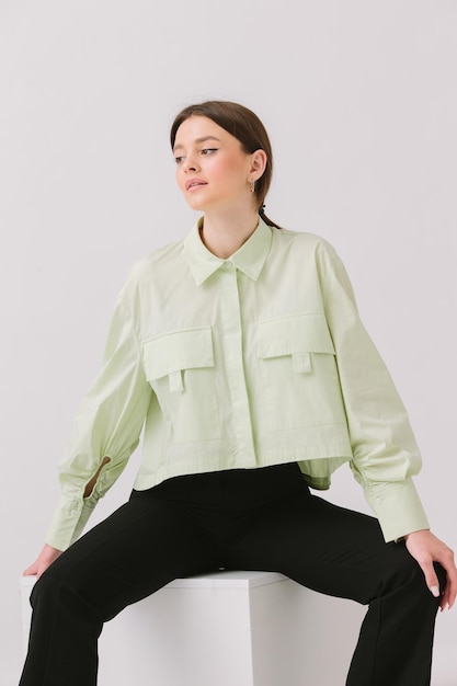 A woman sits on a stool in a green shirt