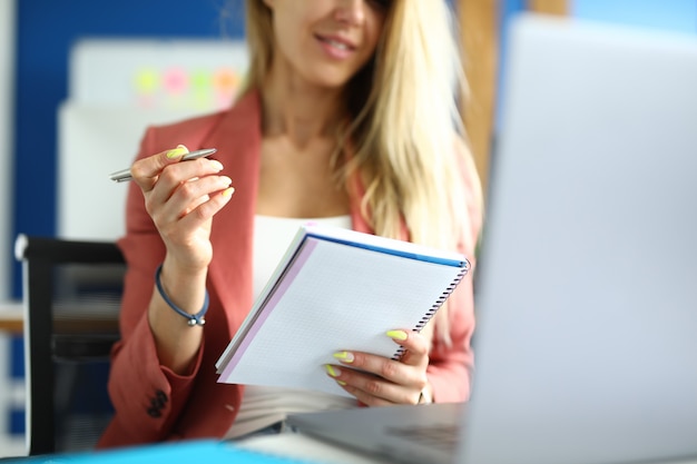 Woman sits at workplace with notebook pen in her hands. Online vocational training concept