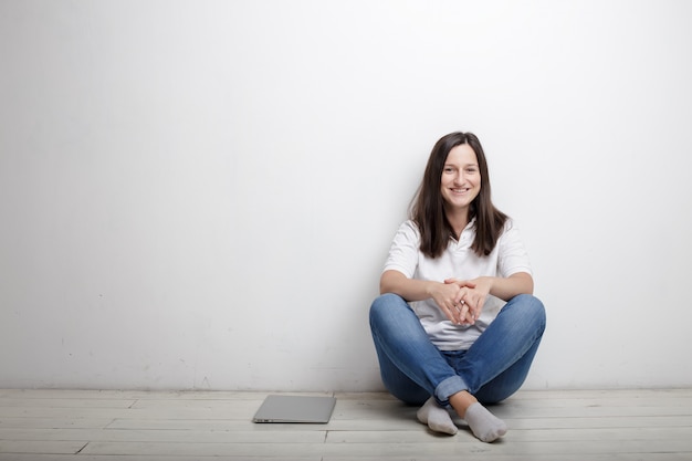 Woman sitting against the wall on the floor