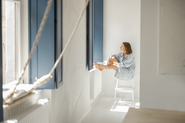 Woman sitting alone by the window at home